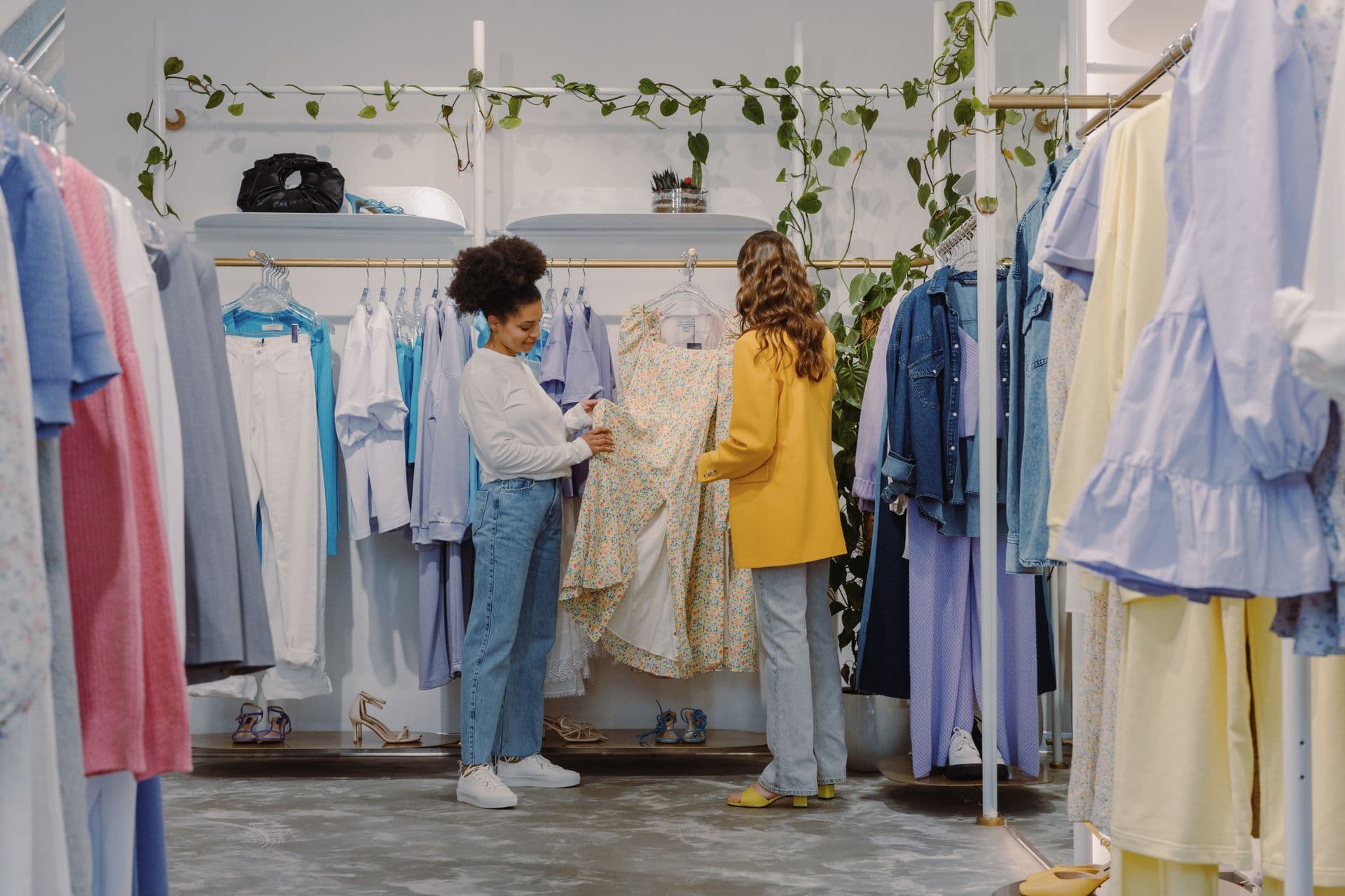 Two women browsing clothes on the racks of a bright boutique