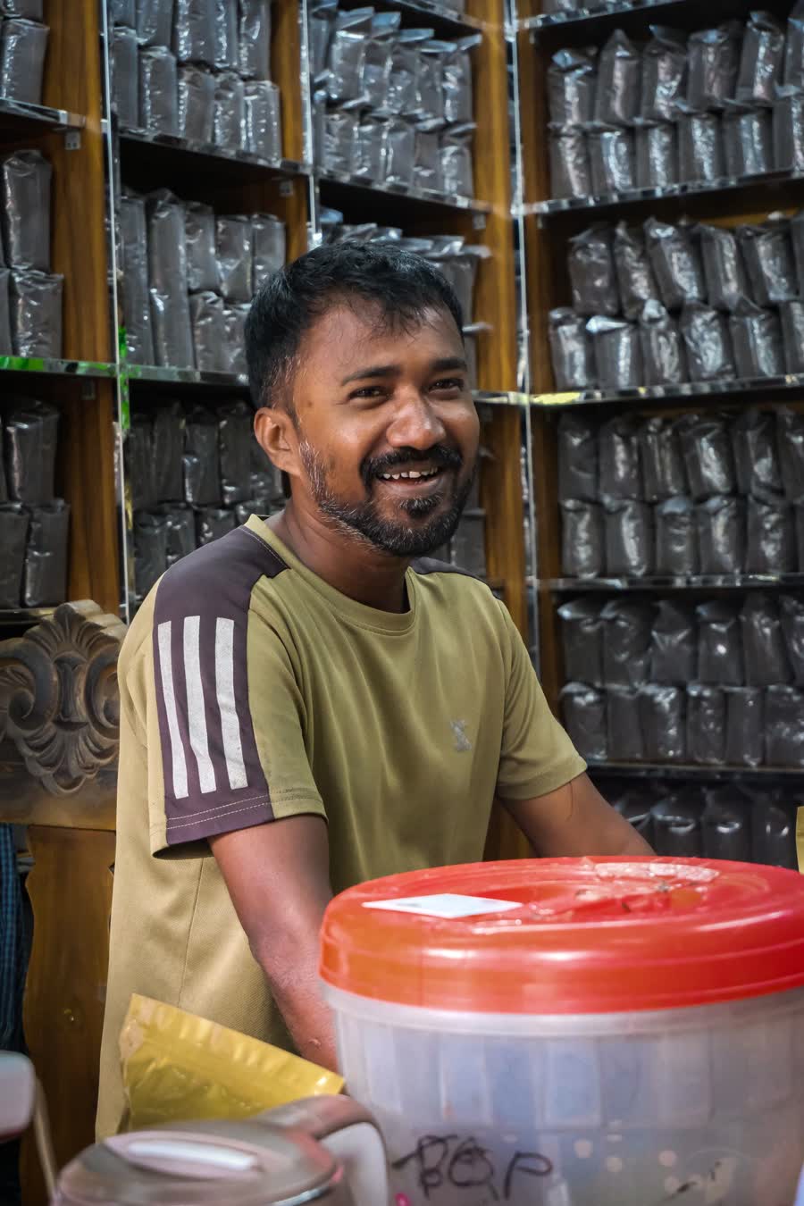 A shopkeeper smiling behind the counter of their store